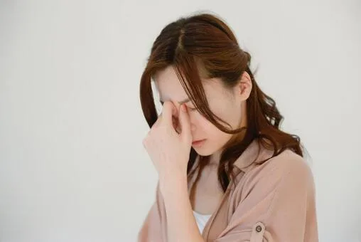 眉間を押さえる女性