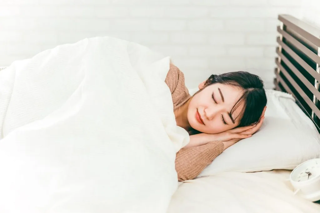 ベッドで寝る女性