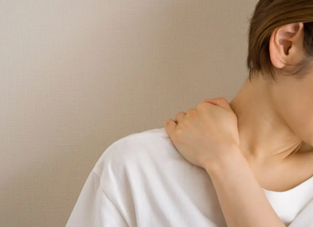 右肩を押さえる女性