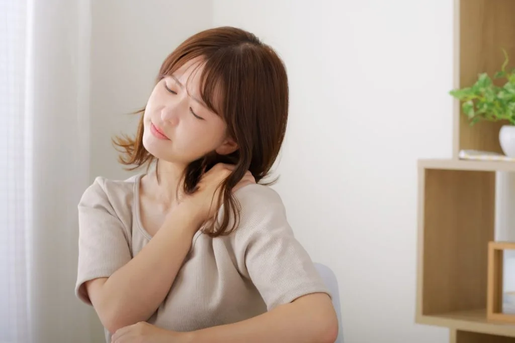 右手で首の左側を押さえる女性