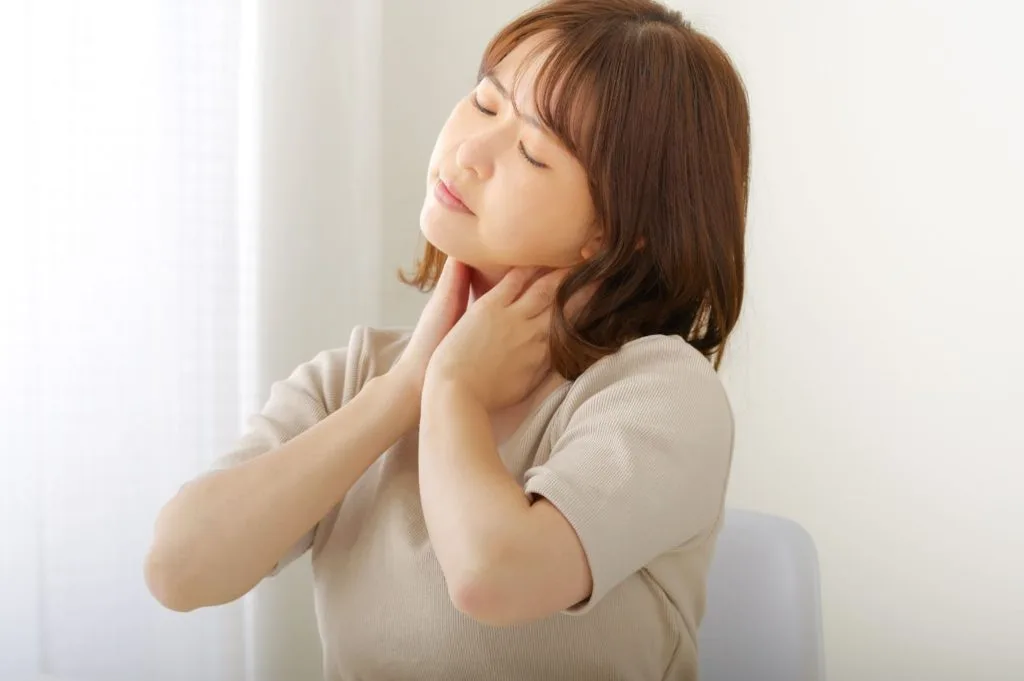 両手で首を押さえて首凝りを気にする女性