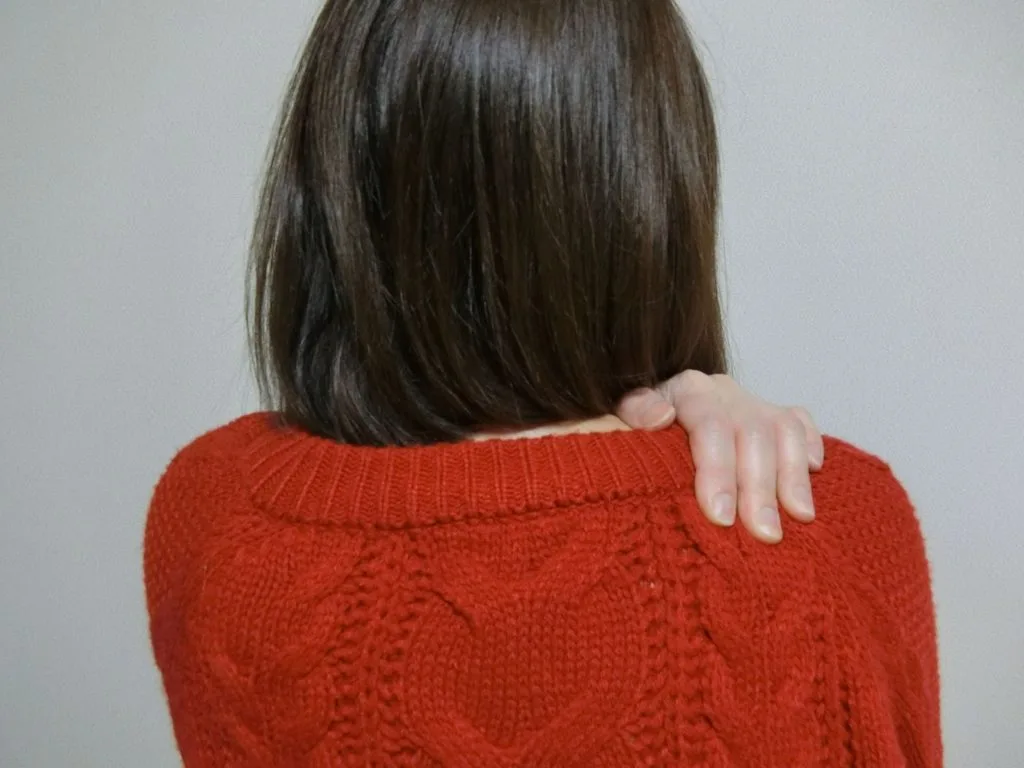 左手で右肩を押さえる女性