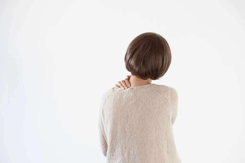 肩の辺りを気にする女性