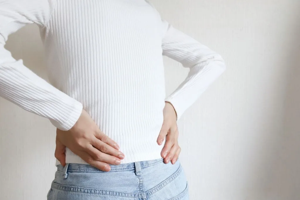 腰の辺りを気にする女性