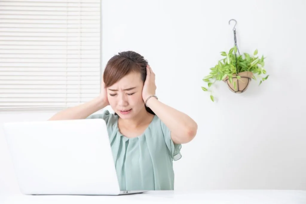 頭を抱えて辛そうにする女性