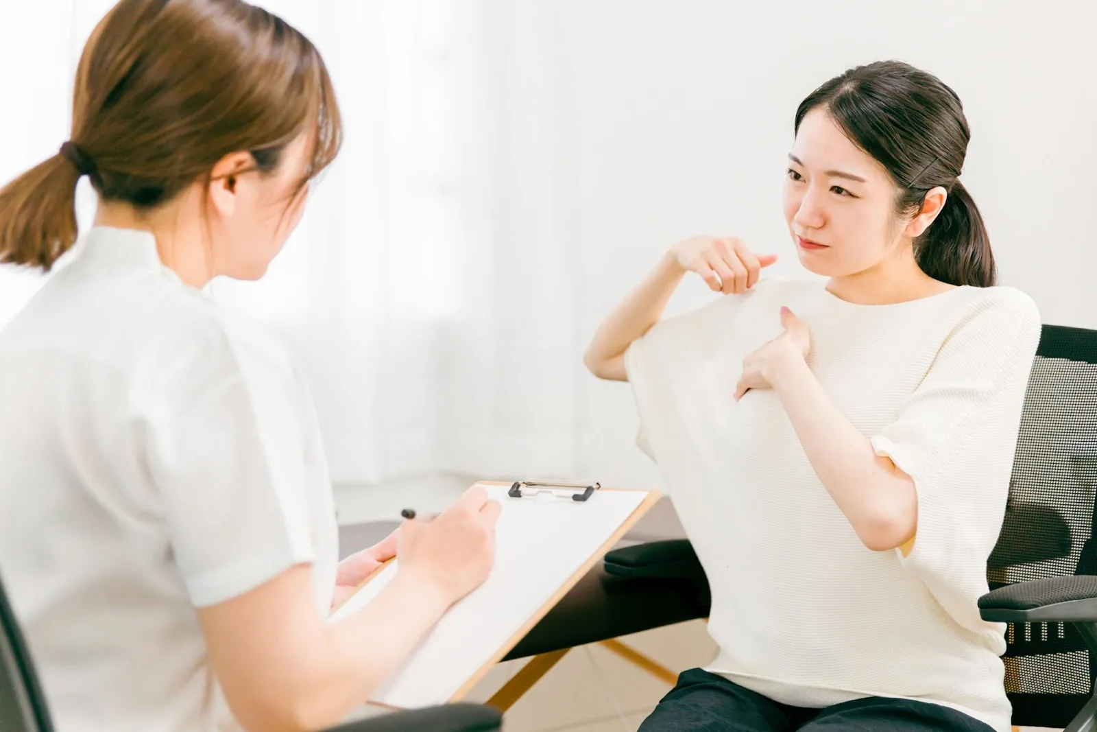 肩こりを相談する女性