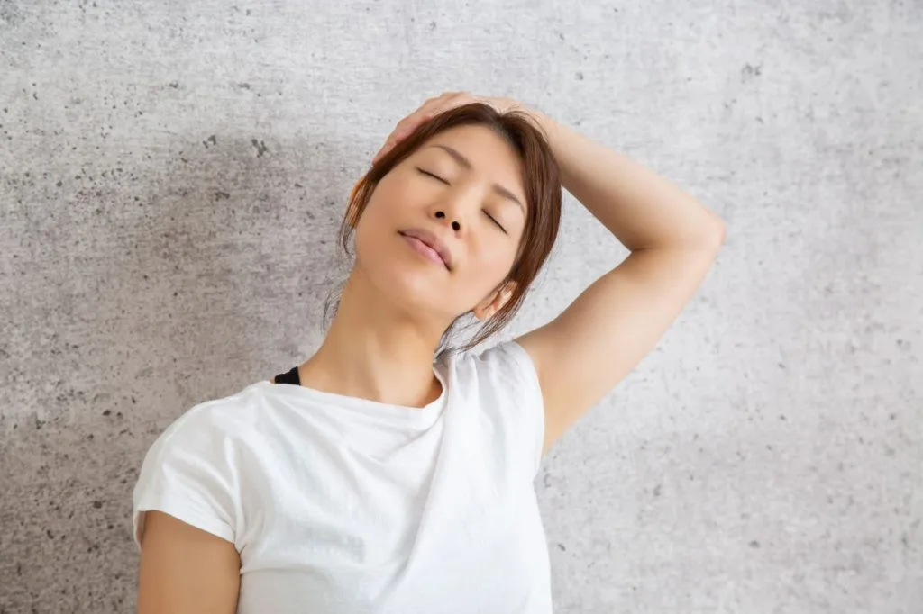 左手を使って首を伸ばす女性