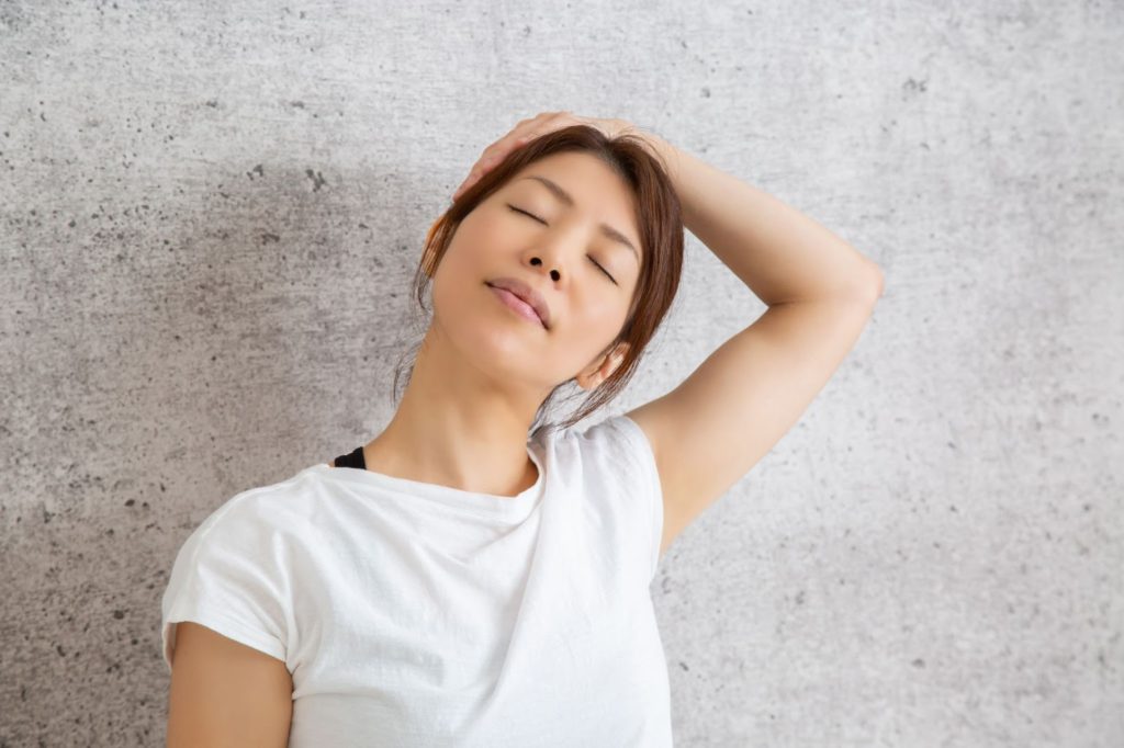 左手を使って首のストレッチをする女性