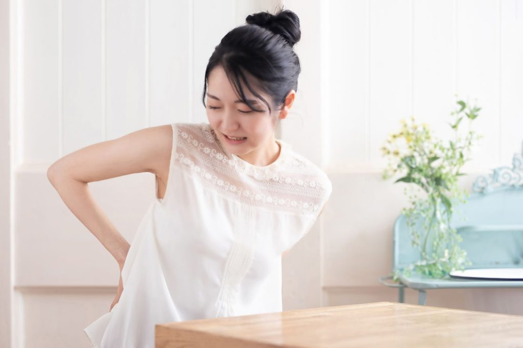 腰に手を当てて痛がる女性