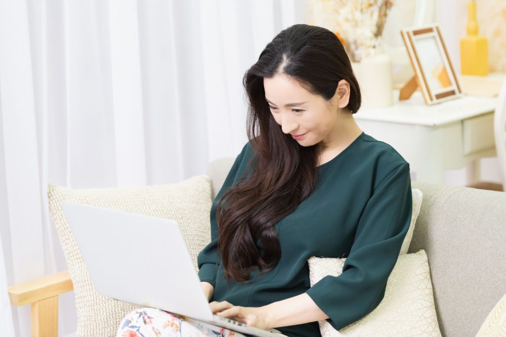 ソファーに座りながらパソコン作業をする女性