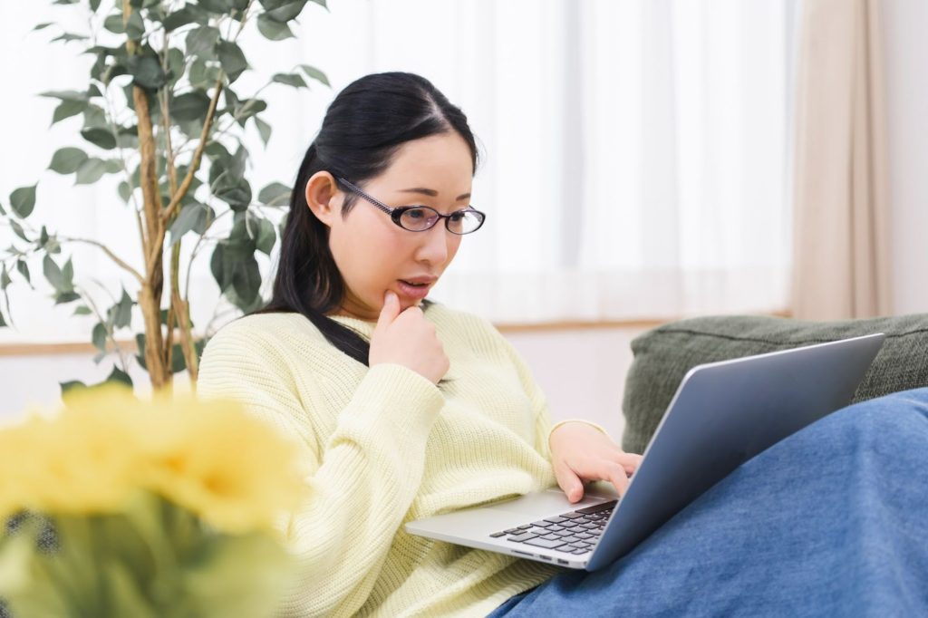 座りながらパソコン作業をする眼鏡の日本人女性
