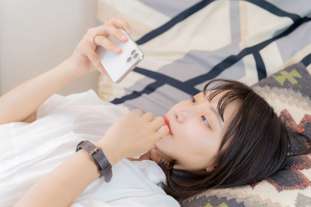 寝ながらスマホを見る女性