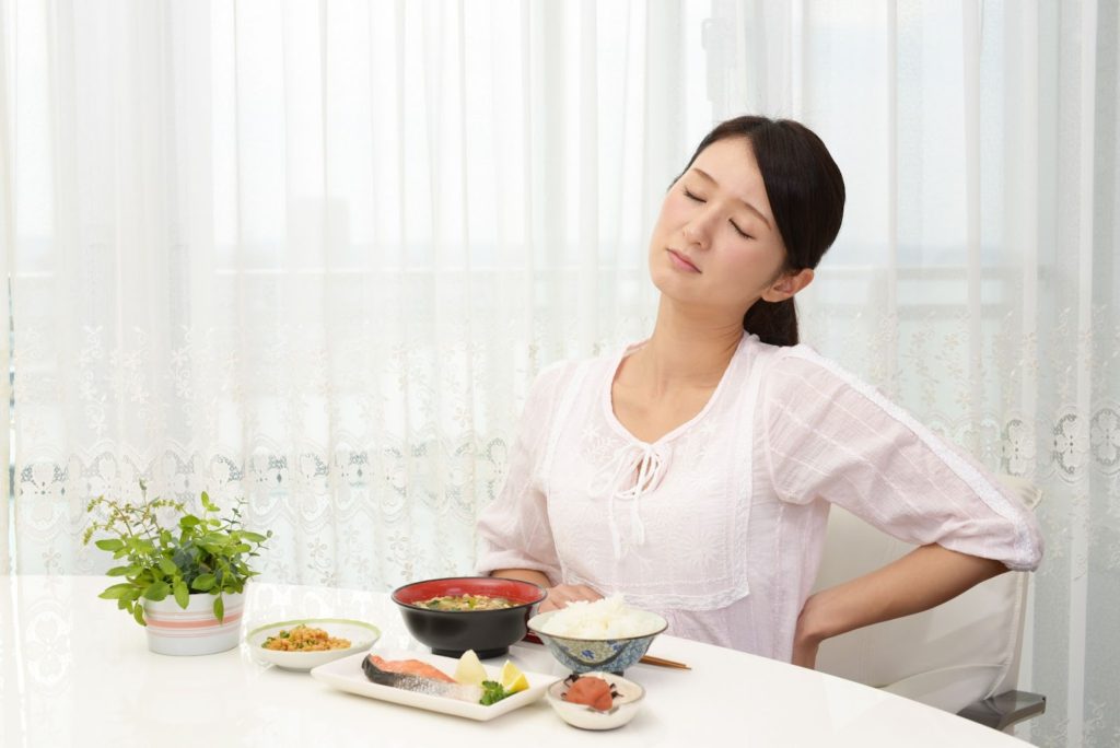 食事中に腰の辺りを気にする女性