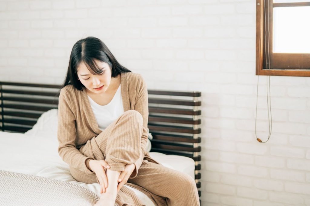 ベッドの上で足を気にする女性