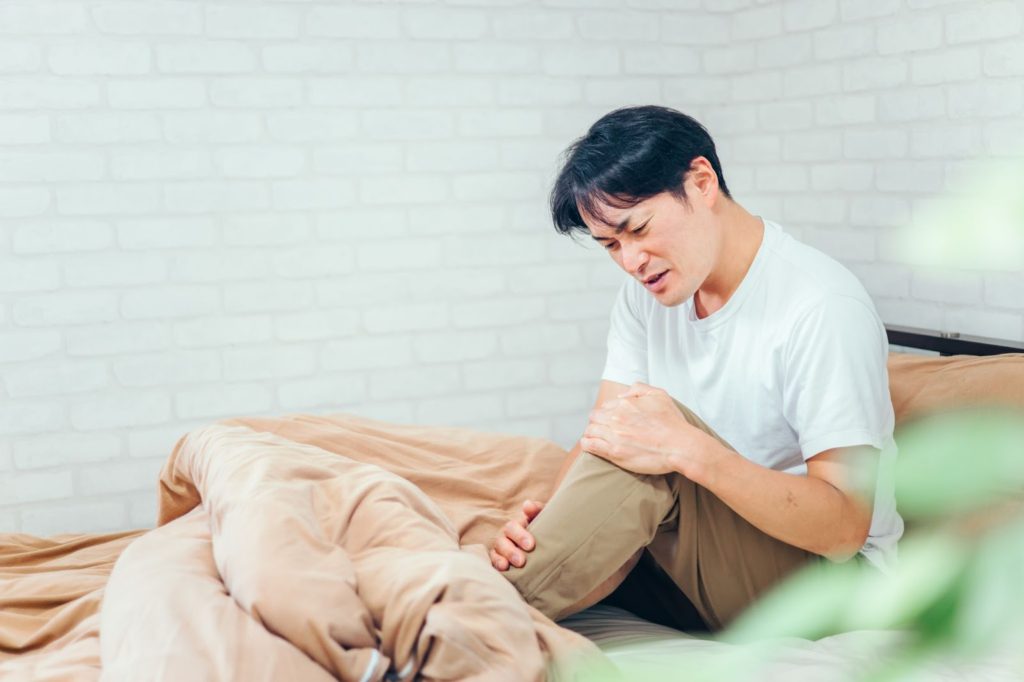 膝を抱えて足を気にする男性