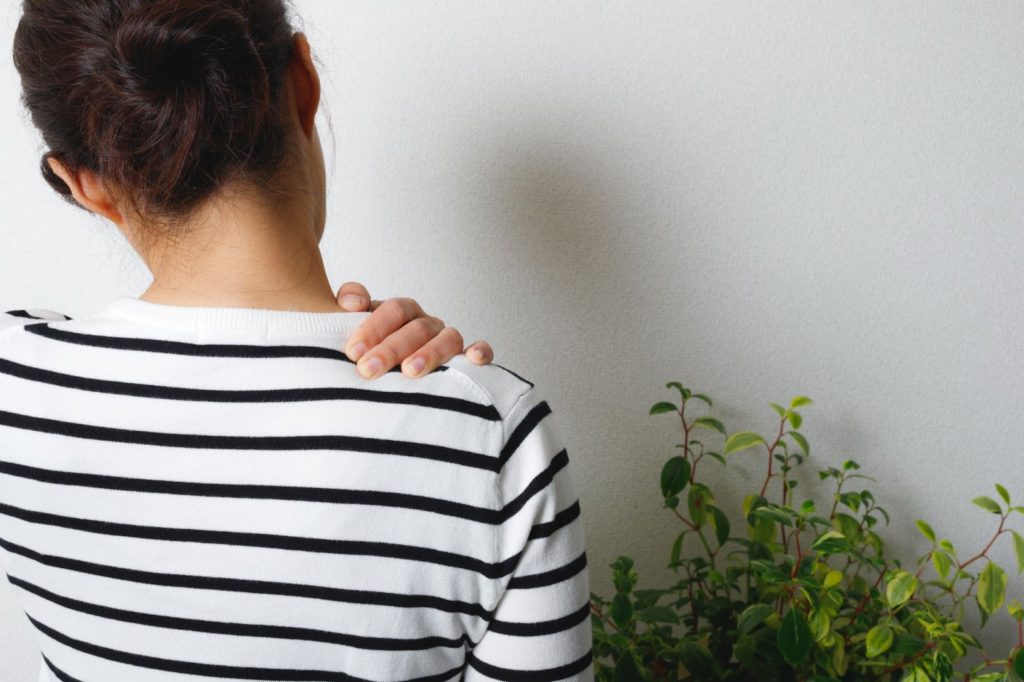 肩の辺りを気にする女性